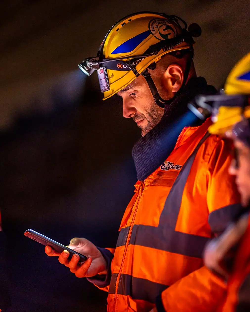 Collecte de donnes hors ligne lors dun chantier de nuit avec un technicien tenant son tlphone la main vtu dun casque avec lampe frontale et tenue de chantier